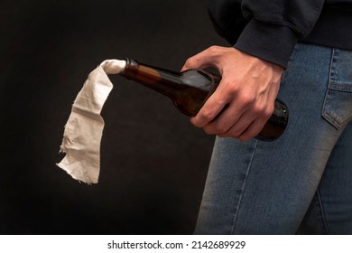 A man holds an unlit Molotov cocktail in his hand on a dark background, close-up, selective focus.