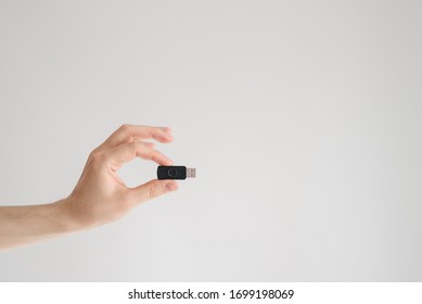 man holds usb flash drive in his hand with his fingertips on a white background. Copy space. Minimalistic shot - Shutterstock ID 1699198069