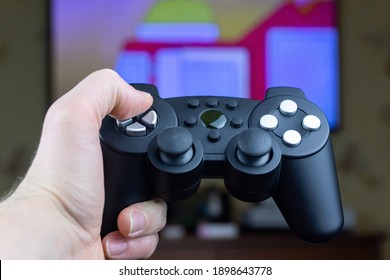 a man holds a wireless gamepad from a video game console in his hand