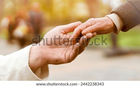 A man holds a woman's hand, carefully supports a loved one, an elderly couple, husband and wife, help each other, hands with wrinkles closeup.