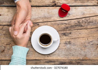 Man Holds Woman's Hand And Gives A Ring In Red Box For Present. Coffee Break Dating Gift