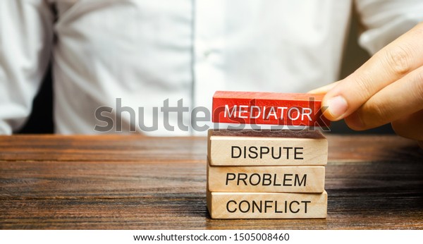 A man holds\
wooden blocks with the word Mediator, dispute, problem, conflict.\
Settlement of disputes by mediator. Dispute Resolution and\
Mediation. Third party,\
intermediary.