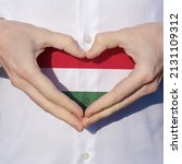 man holidng his hands in heart shaped on white shirt with hungarian flag tricolor colors symbol of the hungarian national day 15th of march .
