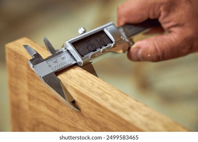 a man in a home carpentry workshop measures boards with a caliper close-up of hands