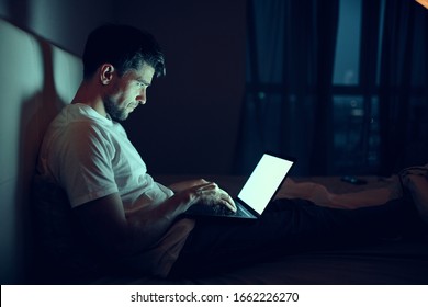 A Man At Home In Front Of A Laptop Watching Movies At Night