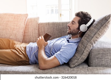 Man At Home On Sofa Listening A Music With A Smartphone