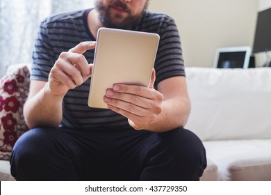 Man at home typing on a tablet