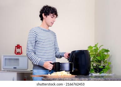 Man At Home Using Air Fryer To Fry Frozen Sliced Potatoes. Using Household Appliances For Cooking. 