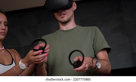 Man At Home Wearing Virtual Reality Headset Holding Gaming Controllers. Active VR Game Virtual Reality Technology Gaming Simulation Helmets. Metaverse Oculus Technology