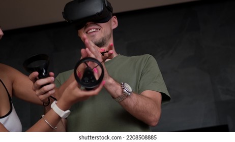 Man At Home Wearing Virtual Reality Headset Holding Gaming Controllers. Active VR Game Virtual Reality Technology Gaming Simulation Helmets. Metaverse Oculus Technology