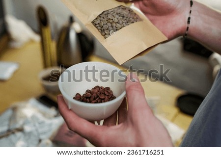 man honding sample plastic cup of freshly roasted brazilian coffee beans
