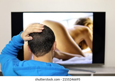 Man in hoodie looking at sensual girl on TV screen. Concept of internet web model, adult movie