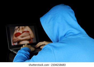 Man in hoodie looking at sensual woman on laptop display. Concept of internet web model, sex video chat, hacking of private data