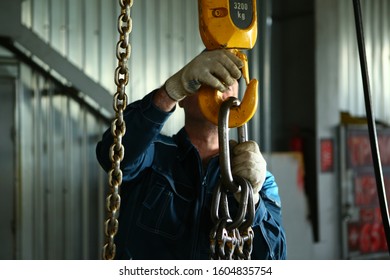 A man hooks a load to the crane.  Work at the factory. - Shutterstock ID 1604835754
