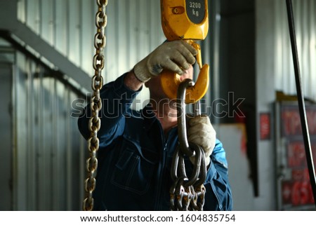 A man hooks a load to the crane.  Work at the factory.