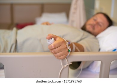 man in a hospital room calling a nurse.A hand holding emergency button in hospital room.Emergency button for hospital patients.