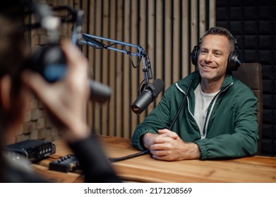 Man host talking to microphone and interviewing a man for a radio podcast.