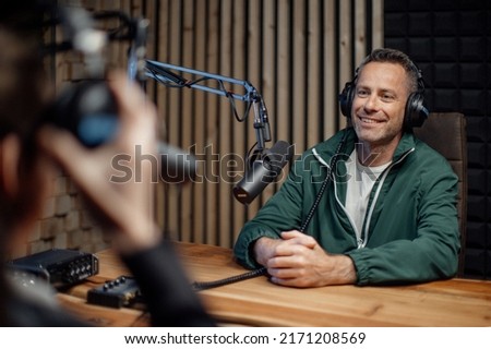 Man host talking to microphone and interviewing a man for a radio podcast.