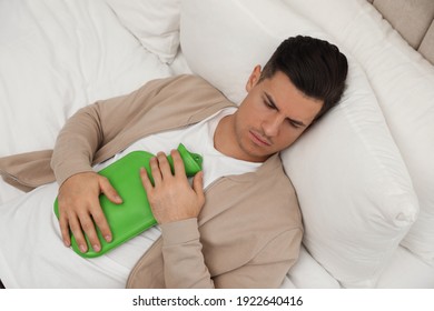 Man with hot water bottle sleeping on bed - Powered by Shutterstock