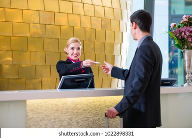 Man In Hotel Check In At Reception Or Front Office Being Given Key Card