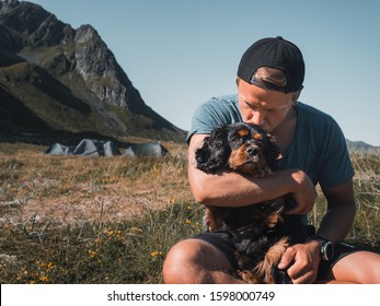 Man hugging a dog on a field camping at the mountains in Lofoten