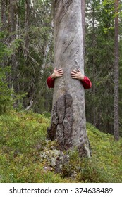 Man hugging a dry tree trunk with only hands visible.