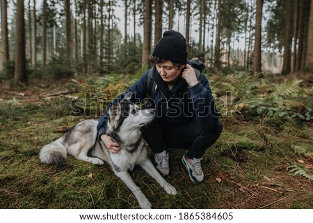 Man hugs his cute white and black husky in the forest at sunset. Friendship between dog and human, they look at each other. Autumn mood outdoors. Enjoy friendship with a pet.