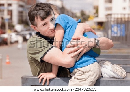 A man hugs his little son tightly, the son and father have not seen each other for a long time and are very happy to meet, the man has returned from a business trip. Father's day