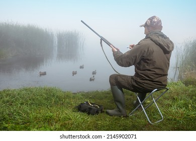 Man Hunter Charges The Shotgun Near Rive Bank At Sunrise.  Duck Hunting.