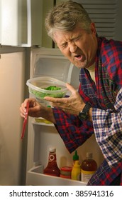 A Man Hunting For A Midnight Snack In The Refrigerator And Has Found A Container With Stinking Spoiled Rotten Food Which Has Made His Face Twisted With His Wretched Disgust.