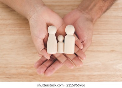 Man husband and Woman wife hands holding wooden peg dolls on the wood table background. family home, foster care, homeless charity support concept, family mental health.
