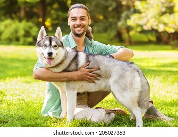 Man And Husky Dog Walk In The Park.