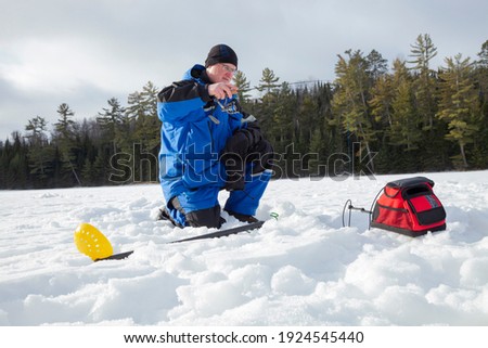 Man ice fishing on a northern Minnesota lake on a sunny winter morning