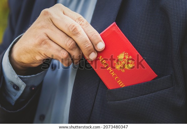 Man With Id Card. Man in a blue suit shows red\
ID card or a pass. An important untouchable employee of the\
ministry is driving a car. Interior Ministry of Russia inscription\
on the red document.