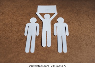 A man with an idea holds a banner in his hand surrounded by two people. The concept of originality, active life position. Paper men. - Powered by Shutterstock