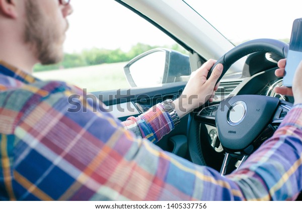 Man ignoring safety and texting onmobile phone\
while driving - Image\
