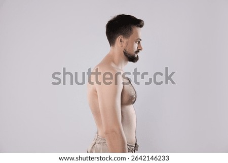 Man with incorrect posture posing on grey background