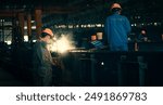 Man Industrial welder worker using a welding torch on metal in a factory. welding worker team working arc weld metal joint production in heavy industry danger and risk workplace with eyes safety.