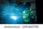 Man Industrial welder worker using a welding torch on metal in a factory. welding worker team working arc weld metal joint production in heavy industry danger and risk workplace with eyes safety.