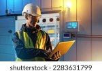 Man is industrialist. Guy near refrigerator. Industrialist with laptop. Setting up functioning of production. Industrialist in factory building. Man in uniform and helmet. Refrigerator at factory