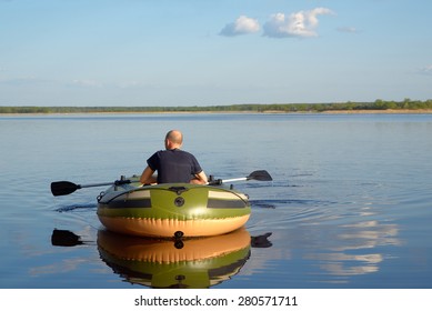 Man In An Inflatable Boat Floats On The River, The View From The Back.