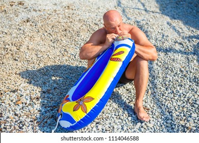 Man Inflates A Children's Rubber Ring For Swimming