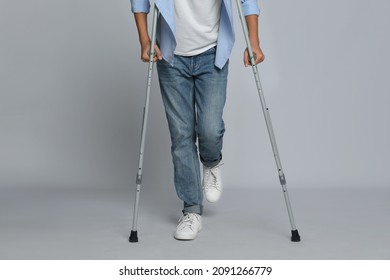 Man with injured leg using crutches on grey background, closeup