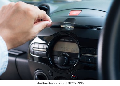The man inserting CD to CD player in the car. Car audio system concept.