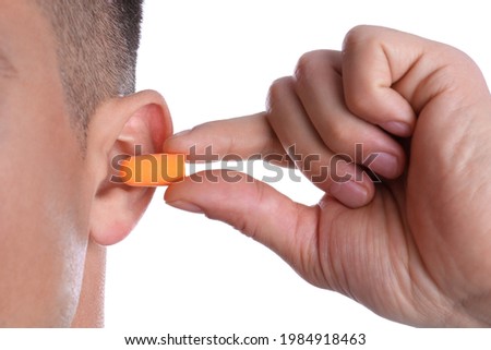 Man inserting foam ear plug on white background, closeup