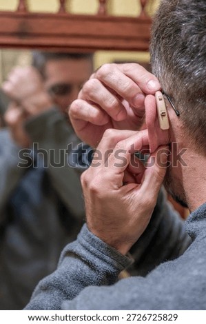 Man inserting hearing aid into ear addressing hearing loss