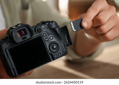 Man inserting SD memory card into photo camera, closeup
