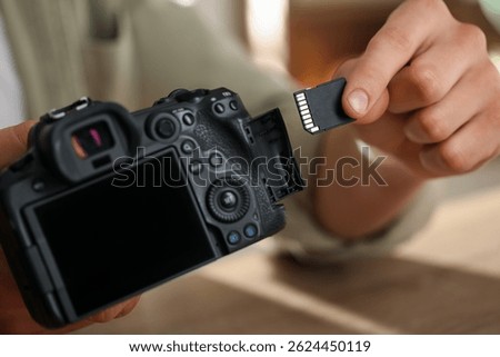 Man inserting SD memory card into photo camera, closeup