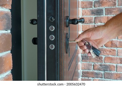 The man inserts the key into the lock to close the armored door of the house.                                - Shutterstock ID 2005632470