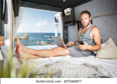 Man inside a camper van using laptop and smartphone - Powered by Shutterstock